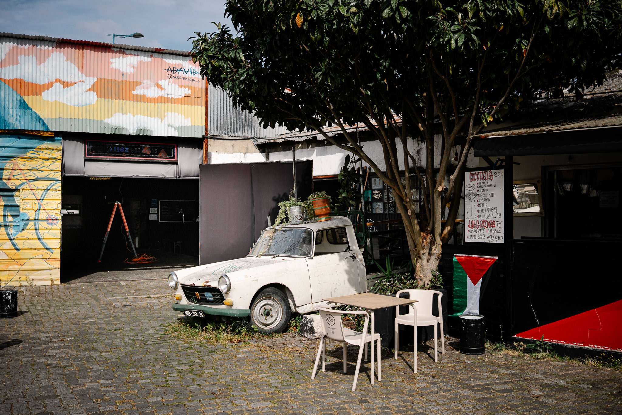 The Arroz Estúdios yard in eastern Lisbon, with a vintage car, a tree and a mural