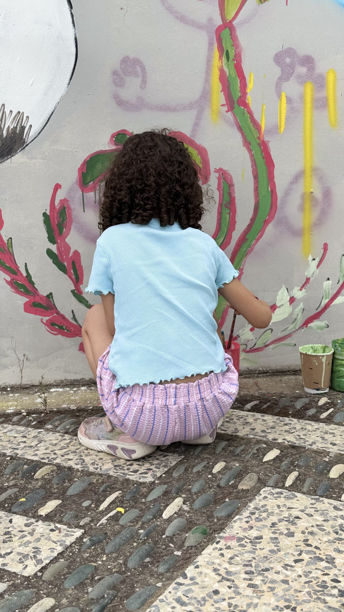A child painting flowers onto the wall